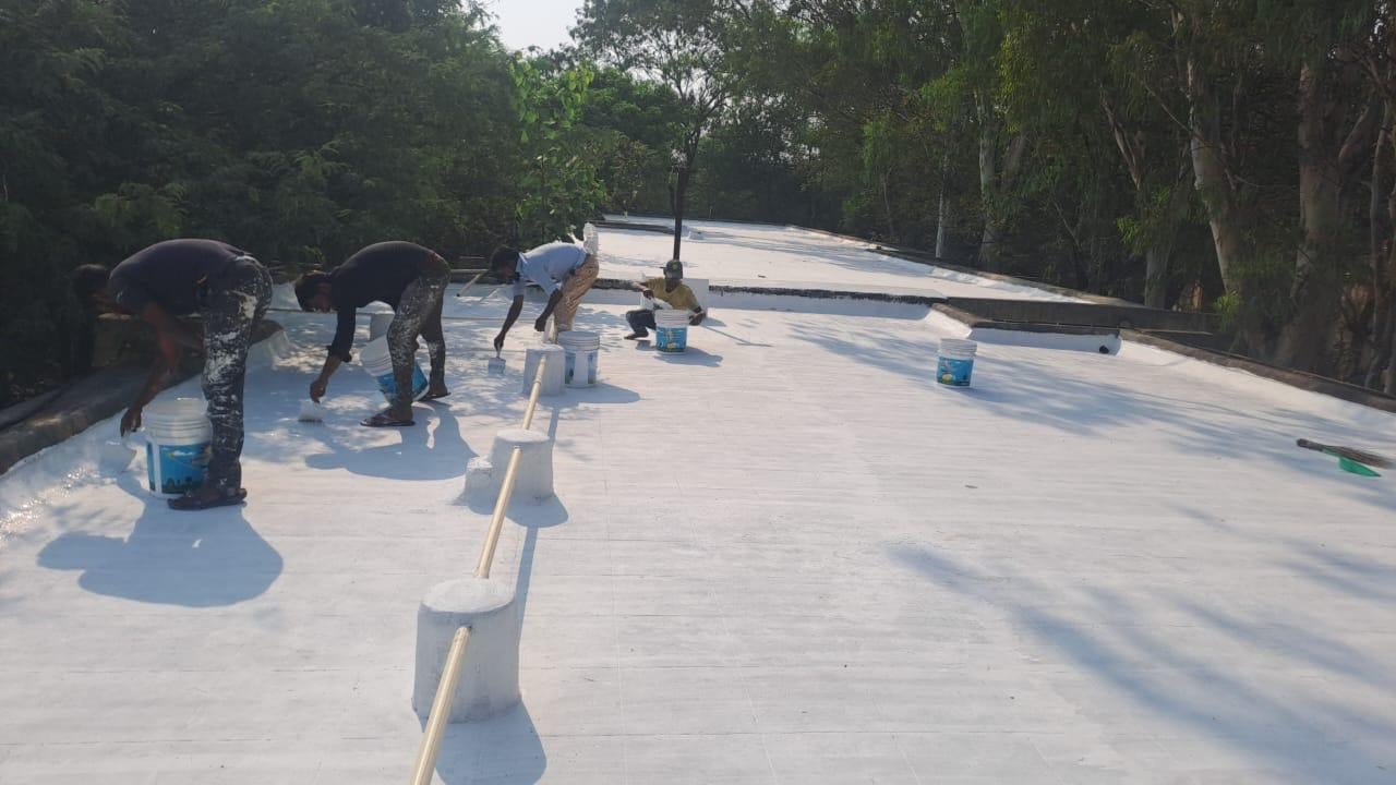Workers applying white cool-roof coating on a campus building roof